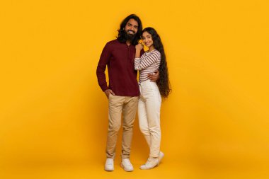 Energetic and excited, the couple points away, drawing attention to something off-camera on the lively yellow backdrop clipart