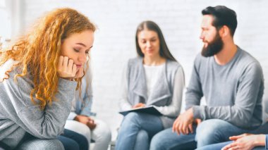 Üzgün kızıl saçlı kadın grup terapisinde oturup sorunlarını düşünüyor.
