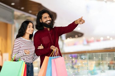 Güzel, genç Hintli çifti seven mutlu adam ve kadın şehir merkezinde birlikte alışveriş yapıyor, renkli kağıt torbaları taşıyor, fotokopi alanına bakıyor ve gülümsüyor. Büyük indirim, reklam.