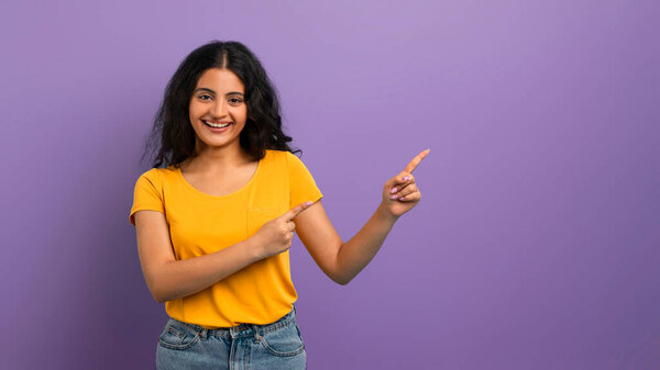 Счастливая женщина с большой улыбкой, указывая пальцами в двух разных направлениях, фиолетовый фон