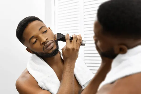 Hombre Afroamericano Con Una Toalla Alrededor Cuello Prepara Barba Usando —  Fotos de Stock