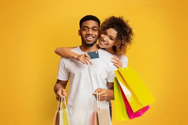 아프리카계 미국인 부부는 자신의 은행에 오렌지 배경에 카드와 쇼핑백으로 — 스톡 사진