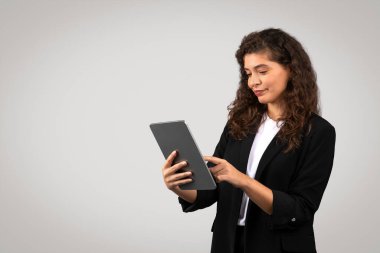 İş kadını dijital tabletle meşgul, muhtemelen raporları gözden geçiriyor veya tarıyor