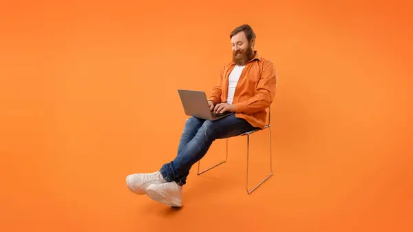 Kafkasyalı Kızıl Saçlı Programcı Dizüstü Bilgisayarında Oturuyor Turuncu Arka Planda — Stok fotoğraf