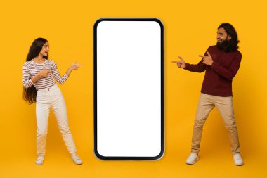 Gülümseyen adam ve kadın etkileşime girer, sarı bir zemin üzerinde boş büyük bir akıllı telefon ekranına işaret ederler.