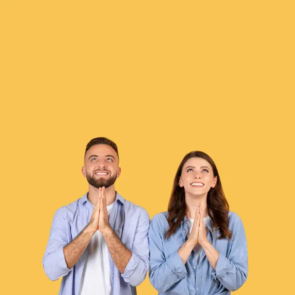 喜びの男と女が一緒に立って 黄色の背景に対して希望に包まれた手で上を見上げます — ストック写真