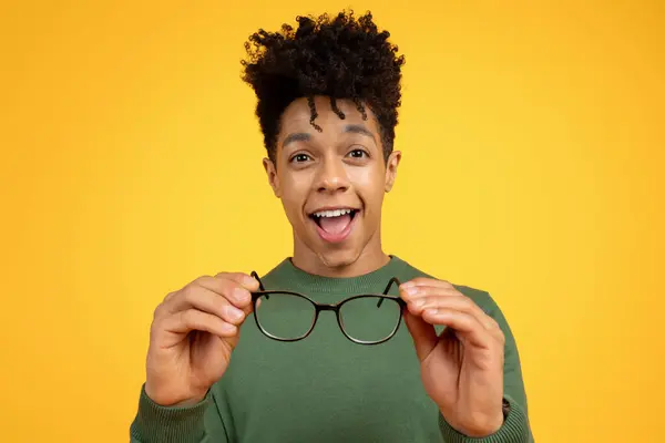 Nadšený Mladý Černoch Kudrnatými Vlasy Vzrušeně Prezentuje Brýle Před Živým — Stock fotografie