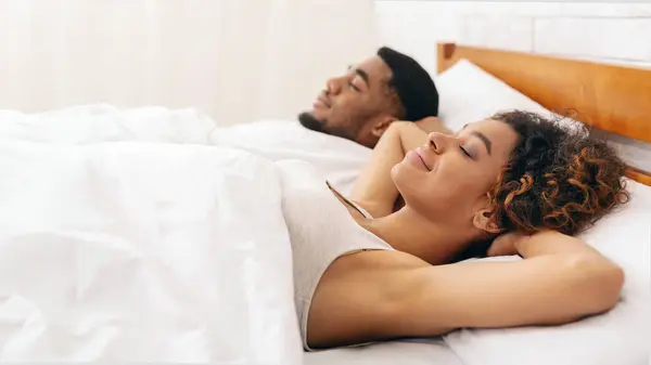 白いベッドの上に横たわるアフリカ系アメリカ人のカップルを撮影した静かなイメージ 穏やかでリラックスした描写 — ストック写真