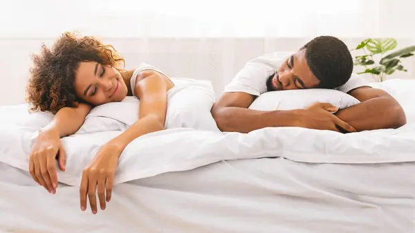 アフリカ系アメリカ人男性と女性は深い眠りに描かれ 個性を象徴する白いベッドに戻って横たわっている — ストック写真