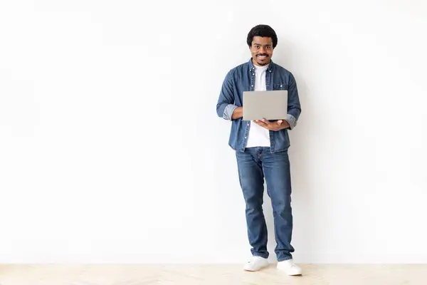 Joven Hombre Negro Comprometido Sosteniendo Ordenador Portátil Con Sonrisa Agradable —  Fotos de Stock