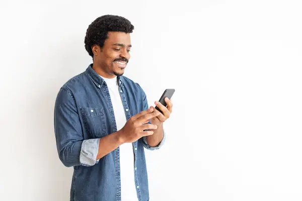 Joven Hombre Negro Alegre Mezclilla Que Involucra Con Teléfono Inteligente —  Fotos de Stock