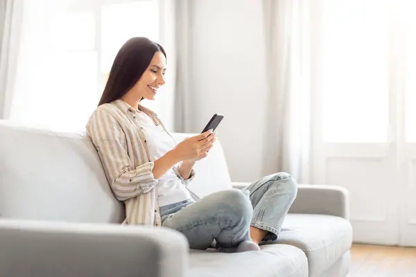 Mulher Sorridente Casualmente Sentada Sofá Segura Smartphone Exalando Uma Sensação — Fotografia de Stock