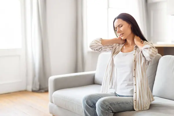 Woman Couch Appears Uncomfortable Her Hands Placed Her Neck Indicating — Stock Photo, Image