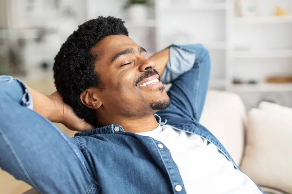 Hombre Negro Está Descansando Sofá Casa Con Las Manos Colocadas —  Fotos de Stock