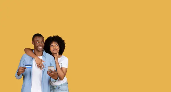 アフリカ系アメリカ人のカップルは オンラインショッピングやデジタル決済を象徴するクレジットカードとスマートフォンを提示します — ストック写真