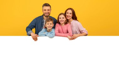 Gülümseyen aile boş beyaz bir tahtanın üzerine bakıyor, reklamlar için mükemmel ya da sarı arkaplanda kopya alanı modeli