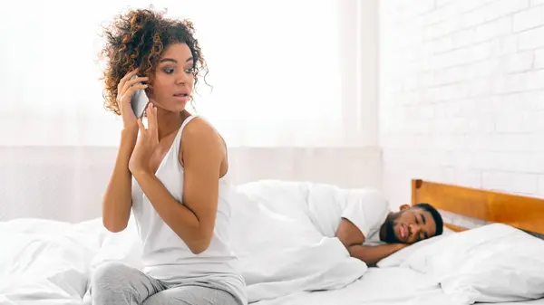 Mujer Afroamericana Habla Por Teléfono Junto Pareja Dormida Retratando Las — Foto de Stock