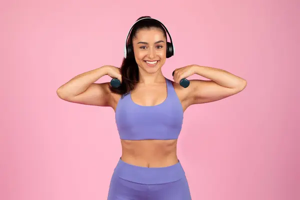 Joyful Woman Wearing Headphones Workout Clothing Flexes Her Muscles Smiles — Stock Photo, Image