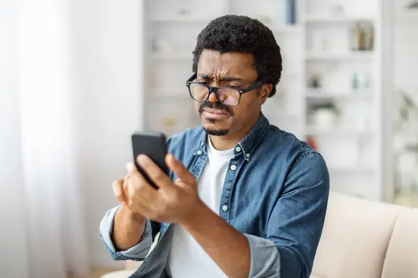 Hombre Negro Entrecierra Los Ojos Teléfono Con Una Expresión Desconcertada —  Fotos de Stock