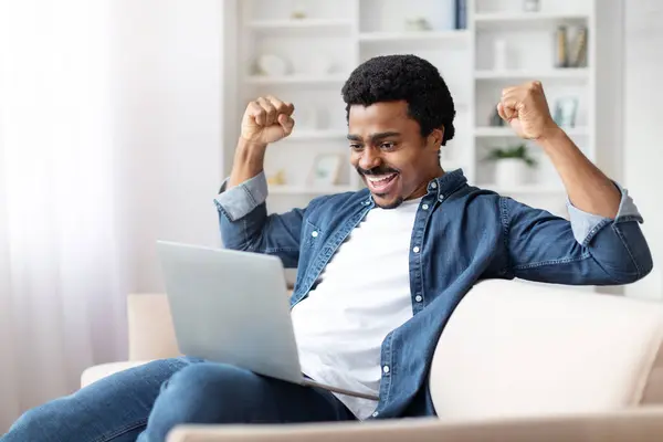 Hombre Negro Encantado Celebrando Éxito Con Ordenador Portátil Casa Sentado —  Fotos de Stock