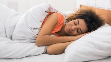 Uyku, konforlu ve blissfully yatakta yatan bir Afrikalı-Amerikalı kadın