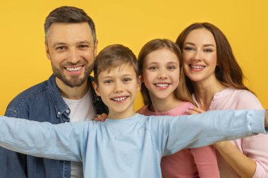 İki çocuk ve mutlu ebeveynle sıkı bir aile kucaklaşması, dört mutlu yüzü yakından görmek, selfie çekmek.