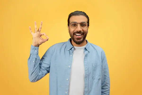 Usmívající Vousatý Východní Muž Brýlích Dává Znamení Rukou Žlutém Pozadí — Stock fotografie