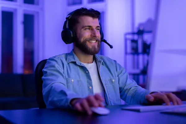 Cheerful Young Bearded Man Wearing Headset Smiles While Engaged Online — Stock Photo, Image