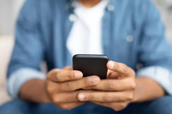 Siyah Adam Kanepeye Oturmuş Kendini Cep Telefonuna Kaptırmış Kaydırıyor Daktilo — Stok fotoğraf