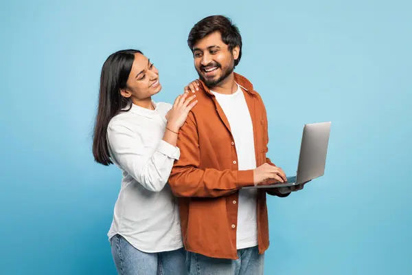 ヒンドゥーの男性と女性は ラップトップ画面を見ながら近くに立って微笑んで デジタル体験を共有します — ストック写真