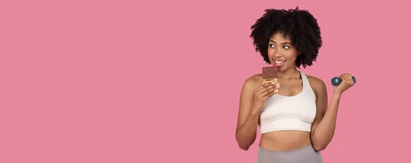 African American Woman Balances Indulgence Fitness Playfully Eating Chocolate While — Stockfoto