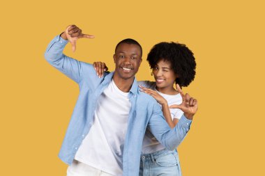 Genç ve neşeli bir Afro-Amerikan çifti birlikte duruyor, sarılıp sarılıyorlar ve eğleniyorlar.
