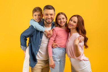Anne ve çocuğun sarı bir stüdyo arka planında sıkıca sarıldıkları sıcak bir aile anı.