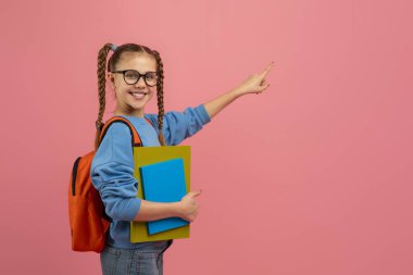 Gözlüklü ve sırt çantalı genç kız pembe arka planda, fotokopi alanı