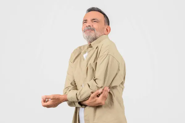 Äldre Man Beige Skjorta Gnuggar Armbågen Poserar Mot Vit Bakgrund — Stockfoto