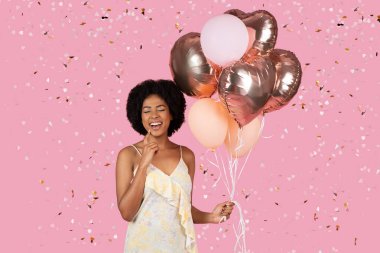 Excited African American woman with a mixture of pink and heart-shaped balloons among falling confetti clipart