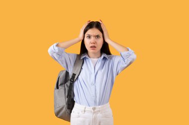 Sırt çantası olan kafası karışmış genç bir kadın, endişe ve şaşkınlığı resmeden sarı bir arka planda strese girer.