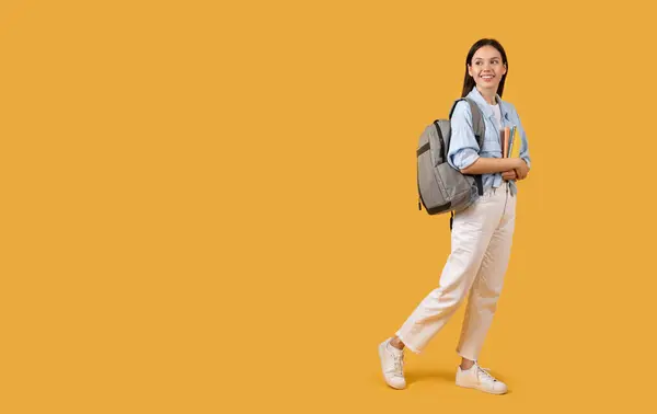 Sırt Çantası Parlak Sarı Arka Planda Bir Yığın Kitapla Yürüyen — Stok fotoğraf