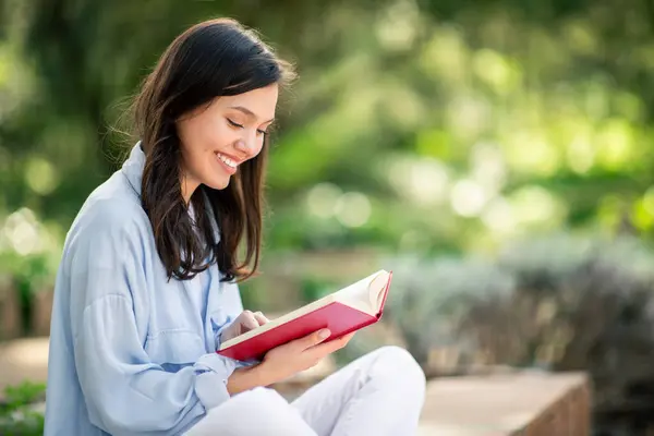 Innehåll Ung Kvinna Tycker Att Läsa Röd Bok Medan Sitter — Stockfoto