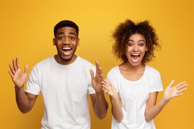 İnanılmaz Surprised Afro-Amerikan erkek ve kadın mutlu hayretle, turuncu arka plan ellerinde yetiştirme