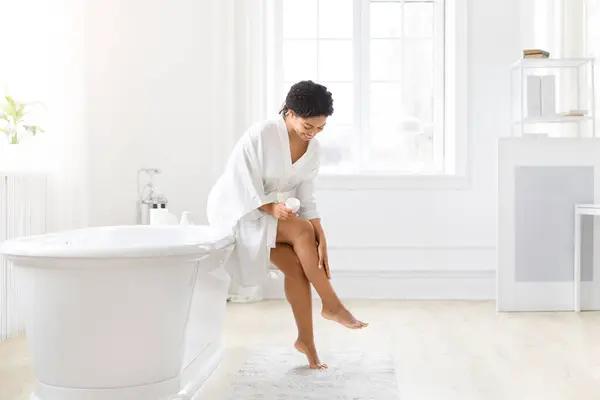 身着浴衣的非洲裔美国女性被告知要检查她们腿上的皮肤 这凸显了她们的自我护理习惯 — 图库照片