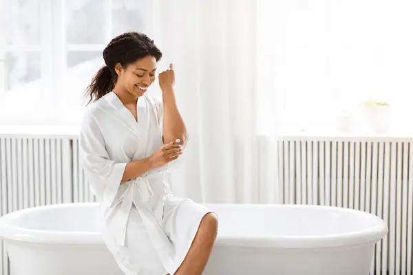 Zufriedene Afroamerikanerin Weißen Bademantel Sitzt Rand Einer Badewanne Einem Sauberen lizenzfreie Stockbilder