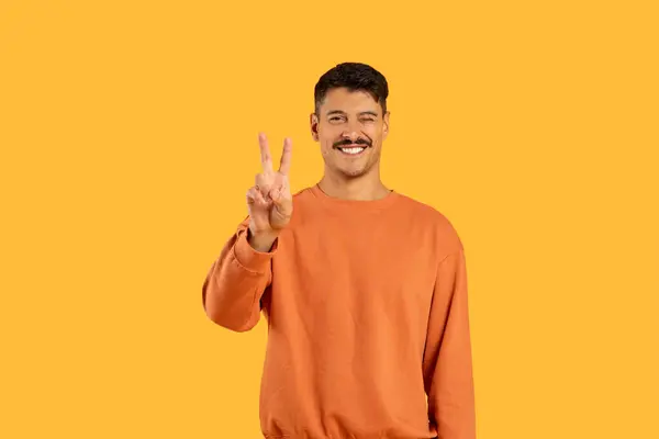 黄色の指で勝利または平和サインのためのVを示すカジュアルな摩耗で口ひげのある笑顔の男 — ストック写真