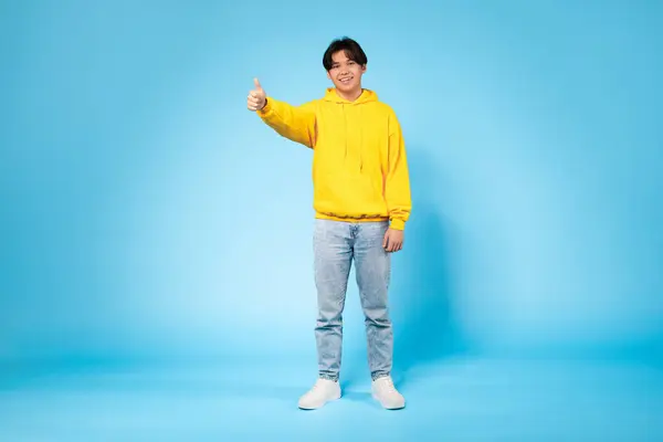 Delighted Young Asian Guy Yellow Sweatshirt Gives Thumbs Expressing His — Stock Photo, Image