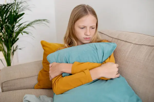 Teen Girl Sitting Sofa Hugging Cushion Somber Expression Her Face — Stock Photo, Image