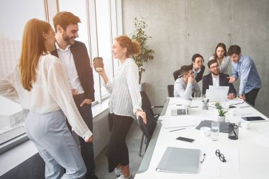 İyi aydınlatılmış bir toplantı odasında takım çalışması ve işbirliği ima eden dinamik bir iş adamı grubu görülüyor.
