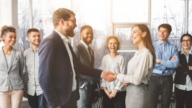 İki iş adamı, başarılı bir anlaşma veya tanıtımı simgeleyen parlak bir ofiste aynı tokalaşmayı paylaşıyor