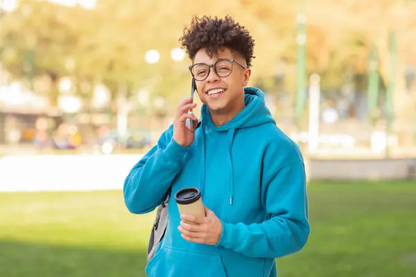 Delighted Young Brazilian Guy Multitasks Sipping Coffee Engaging Phone Conversation — Stock Photo, Image