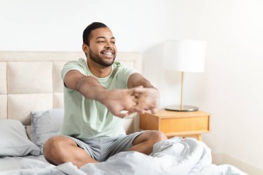 Neşeli bir Afrikalı Amerikalı adam yeni bir günü selamlarken kollarını uzatıyor, neşe ve rahatlama sergiliyor.