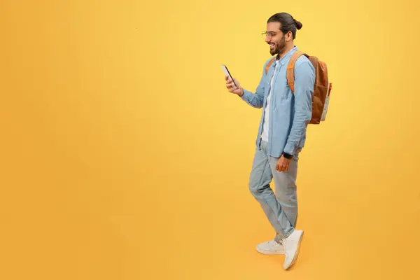 Zwykły Indianin Plecakiem Spacerujący Patrzący Smartfona Żółtym Tle — Zdjęcie stockowe